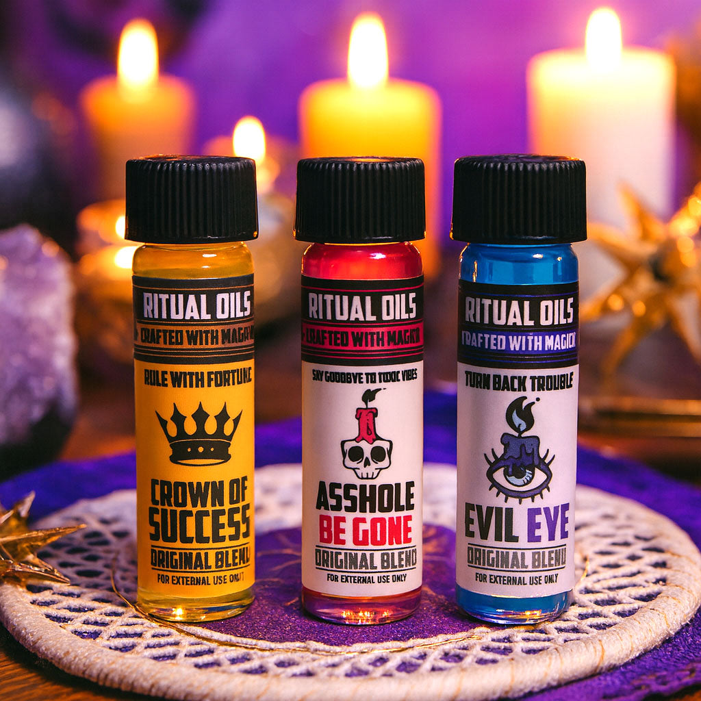 Three bottles of ritual oils with colorful labels on a purple cloth with candles in the background.